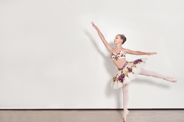 Jovem bailarina realiza exercícios de balé no estúdio contra um fundo branco