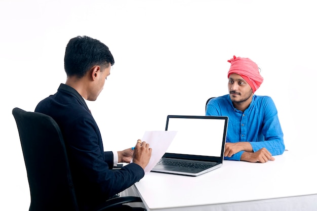 Jovem banqueiro indiano dando algumas informações ao fazendeiro no escritório.