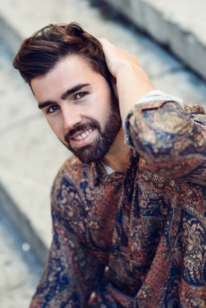 Foto jovem barba, modelo de moda, vestindo camisa em fundo urbano.