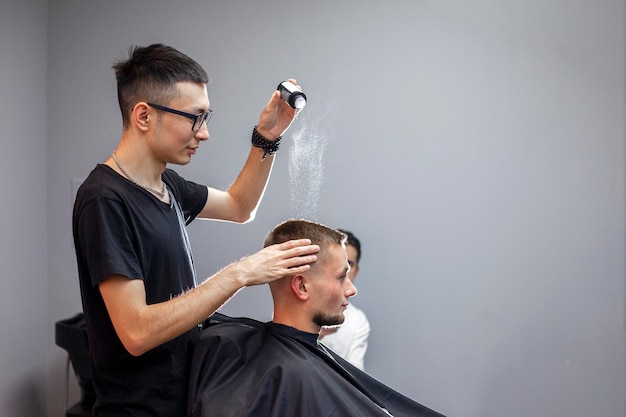 Jovem barbeiro cazaque trabalha em uma barbearia um cara bonito faz estilo de cabelo