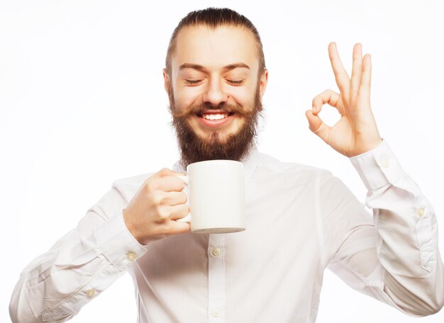 Jovem barbudo bebendo café e aparecendo o polegar.