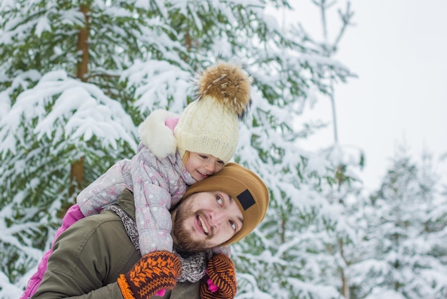 Jovem barbudo com uma menina se divertindo em um bosque nevado no inverno