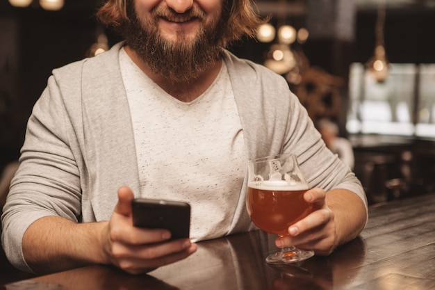 Jovem barbudo desfrutando de beber cerveja no pub