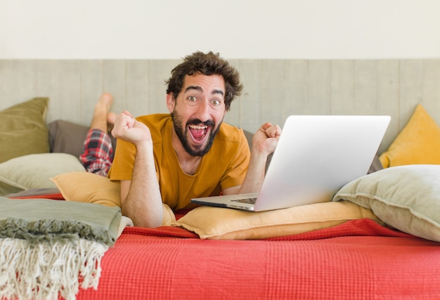 Foto jovem barbudo em uma cama com um laptop
