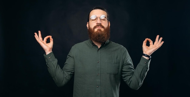 Jovem barbudo está meditando enquanto segura a mão com gesto zen