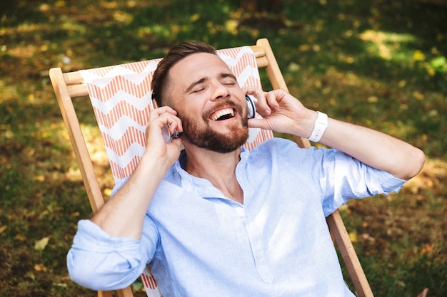 Foto jovem barbudo feliz e animado a ouvir música