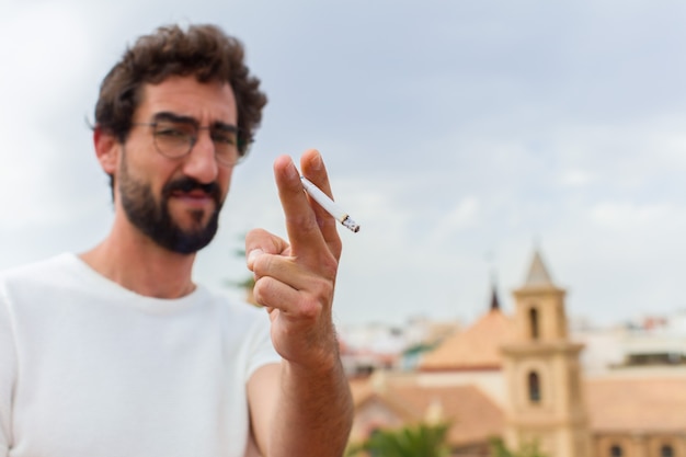 Jovem barbudo fumando um cigarro