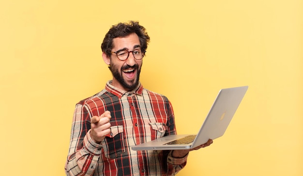 Jovem barbudo louco apontando ou mostrando e um laptop