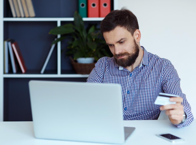 Jovem barbudo paga com cartão de crédito em compras online