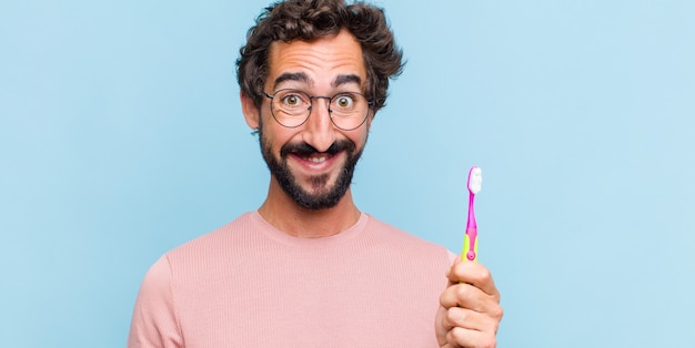 Jovem barbudo parecendo feliz e bobo com um sorriso largo, divertido e maluco e olhos bem abertos