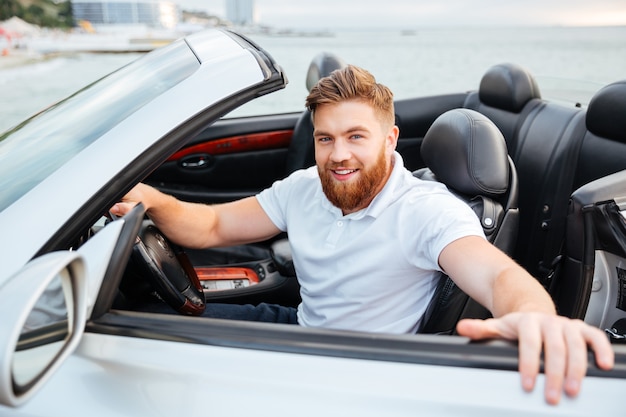 Jovem barbudo sorridente saindo do carro