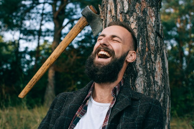 Jovem barbudo sorrindo amplamente na floresta ao ar livre. homem feliz