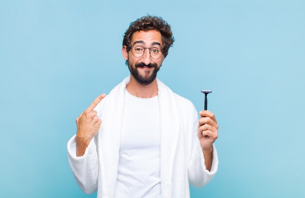 Jovem barbudo sorrindo com confiança apontando para o próprio sorriso largo, atitude positiva, relaxada e satisfeita