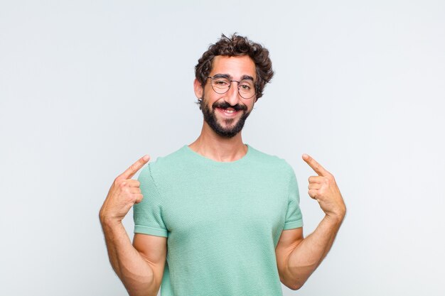 Jovem barbudo sorrindo com confiança apontando para o próprio sorriso largo