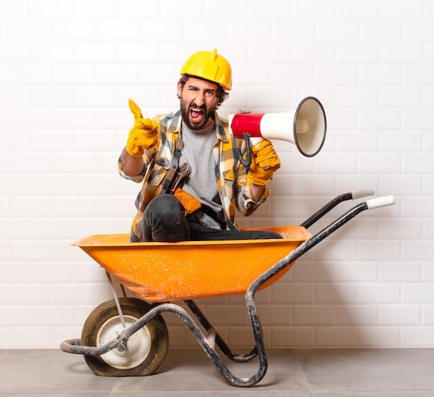 Foto jovem barbudo trabalhador da construção civil em um carrinho de mão