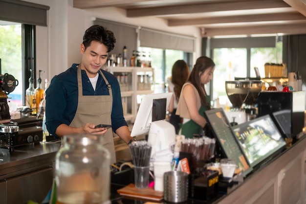 Jovem barista asiático com espírito de serviço com cliente na cafeteria