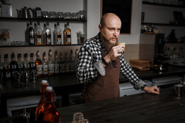 Jovem barista de avental degustação de café no bar em um café moderno