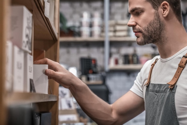 Jovem barista escolhendo café na loja para o cliente