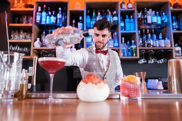 Jovem barman fazendo um coquetel especial para seus clientes Conceito bebe vida noturna divertida