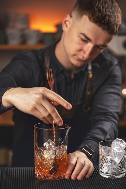 Jovem barman mexendo coquetel alcoólico fresco