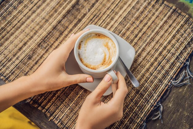 Jovem bebe café em um café nas montanhas