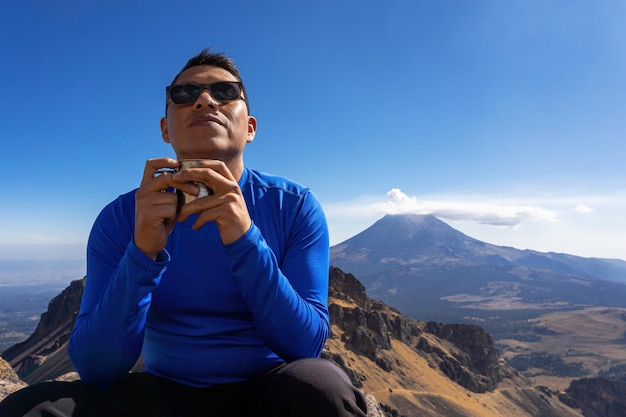 Jovem bebendo café quente na montanha