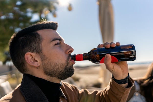 Jovem bebendo cerveja na praia