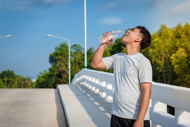 Jovem beber água antes de exercício de treino