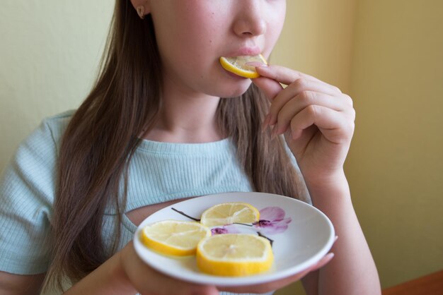 Jovem bela menina comendo limão close-up foto de colheita boca comendo uma fatia de limão