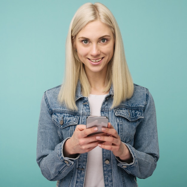 Jovem bela mulher feliz usando telefone inteligente. Isolado em fundo azul