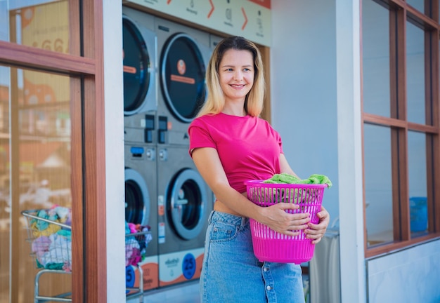 Jovem bela mulher lava e seca roupas na lavandaria