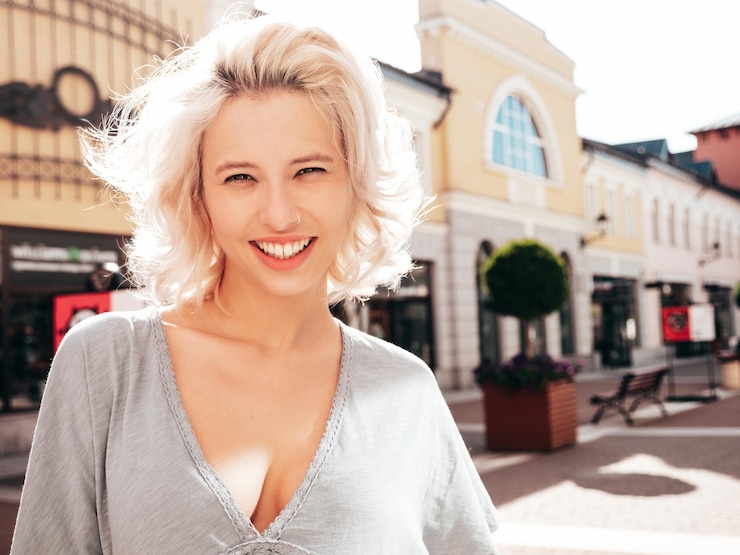 Foto jovem bela mulher loira sorridente em roupas de verão de moda modelo despreocupado posando na rua