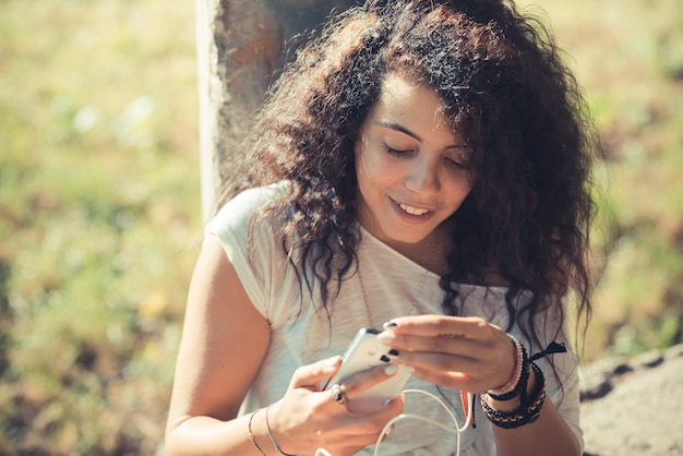 jovem bela mulher morena encaracolado escutando música com smartphone