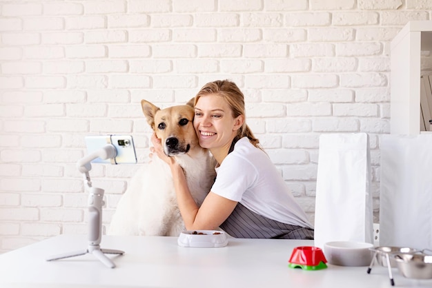 Jovem blogueira caucasiana falando olhando para a câmera tendo fluxo com seu cachorro