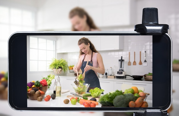 Jovem blogueira e vlogger e influenciadora online transmitem ao vivo um programa de culinária nas mídias sociais usando um smartphone