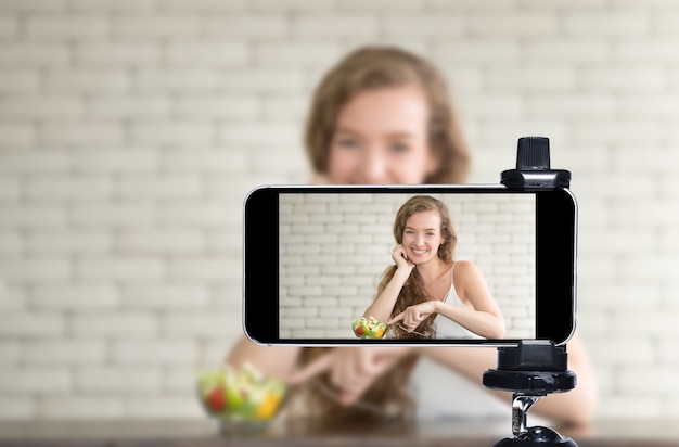 Jovem blogueira e vlogger e influenciadora online transmitem ao vivo um programa de culinária nas mídias sociais usando um smartphone