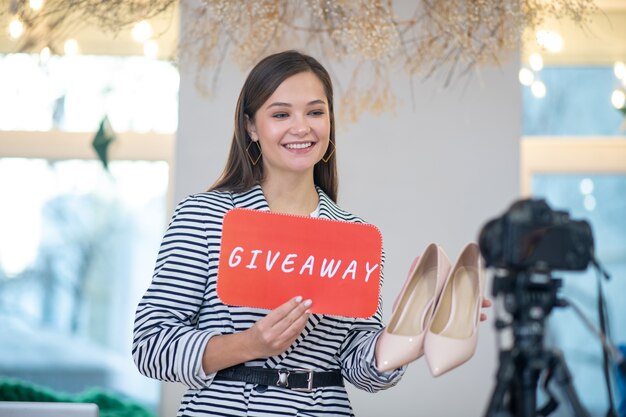 Jovem blogueira positiva sorrindo enquanto promove seu sorteio de sapatos