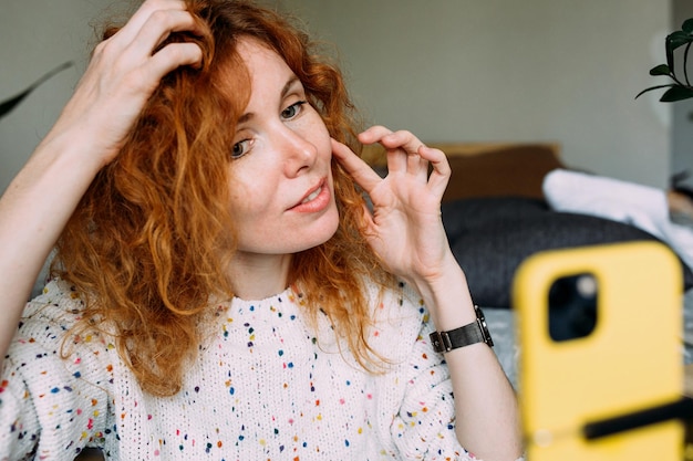 Jovem blogueira ruiva encaracolada filmando tutorial diário para mídias sociais