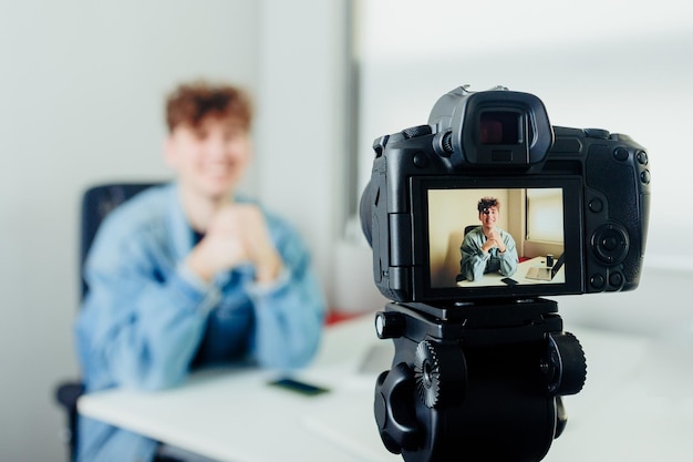 Jovem blogueiro bonito com câmera Homem filmando-se com uma câmera moderna Conceito de blog