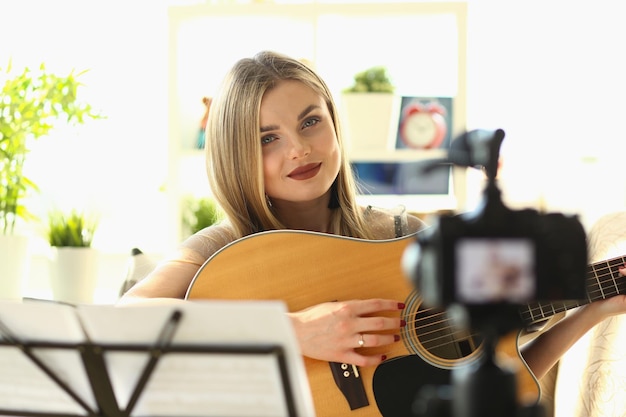 Jovem blogueiro influenciador toca violão filmando um vlog educacional