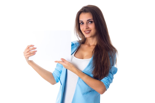 Foto jovem boa mulher de camiseta branca e jaqueta azul segurando uma folha de papel branca no estúdio