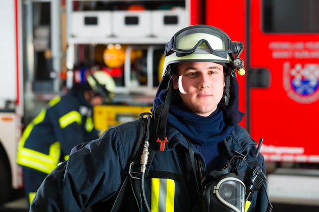 jovem bombeiro de uniforme na frente do caminhão de bombeiros