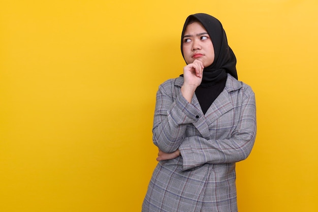 Jovem bonita asiática vestindo blazer e hijab olhando de lado para o espaço vazio para isolamento de propaganda