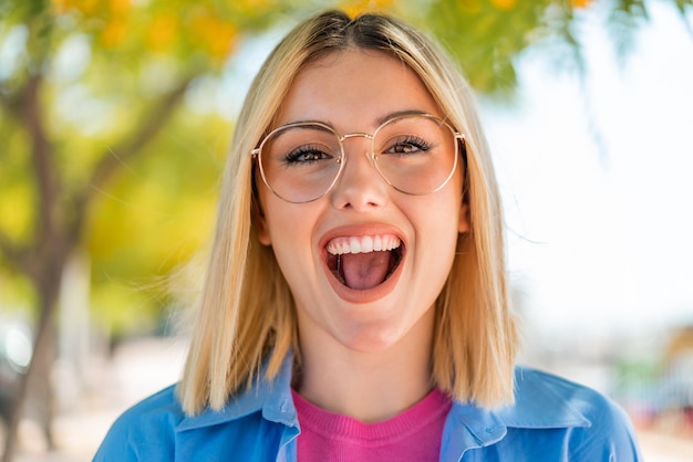 Foto jovem bonita com óculos ao ar livre com expressão facial de surpresa