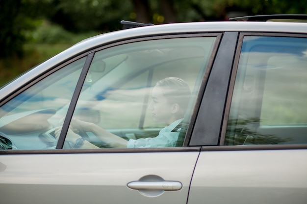 Jovem bonita dirigindo um carro - convite para viajar. Aluguel de carro ou férias