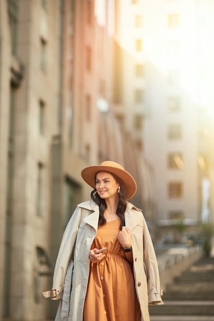 Jovem bonita e elegante mulher caucasiana com vestido longo romântico e chapéu olhando para o lado e