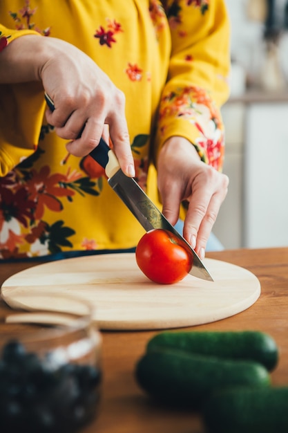 Jovem bonita grávida preparando salada de legumes na cozinha