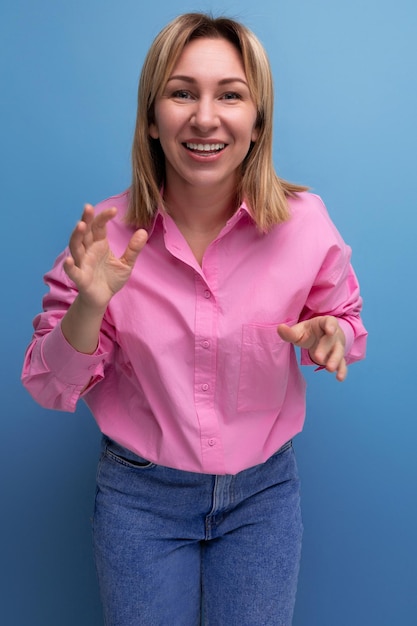 Jovem bonita loira europeia funcionária de escritório mulher com cabelo fluido em uma blusa rosa sorri doce