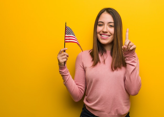 Jovem bonita, segurando uma bandeira dos Estados Unidos, mostrando numbere