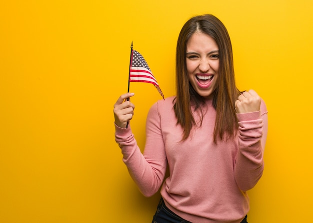 Jovem bonita, segurando uma bandeira dos estados unidos surpresa e chocada